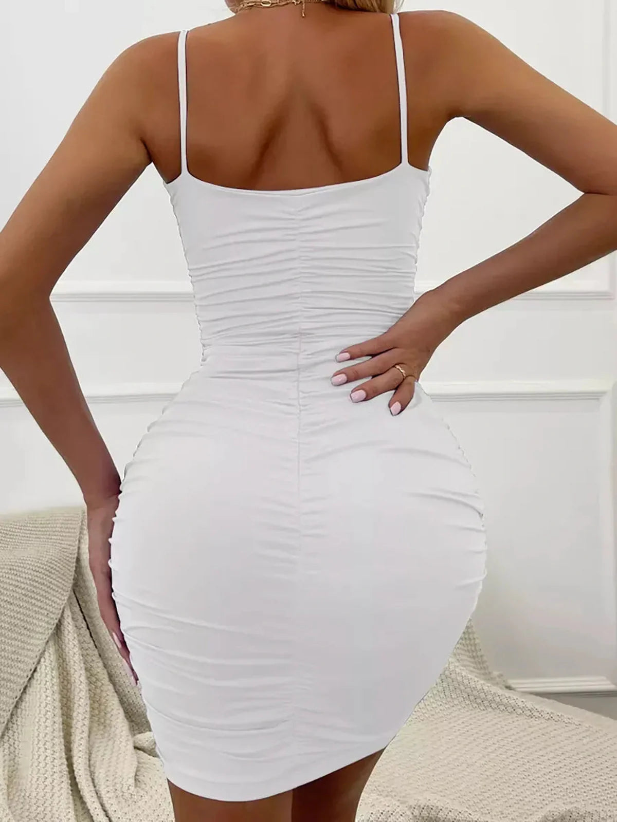 Back view of Sleek Charm Mini Dress, white bodycon dress with ruching and spaghetti straps for stylish summer looks.