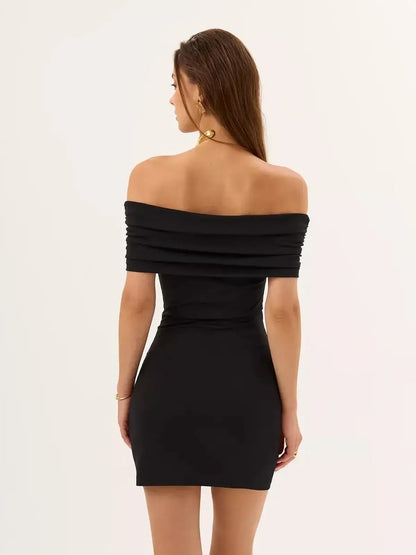 Back view of a woman wearing a black bodycon mini dress with off-shoulder design and ruched detailing.