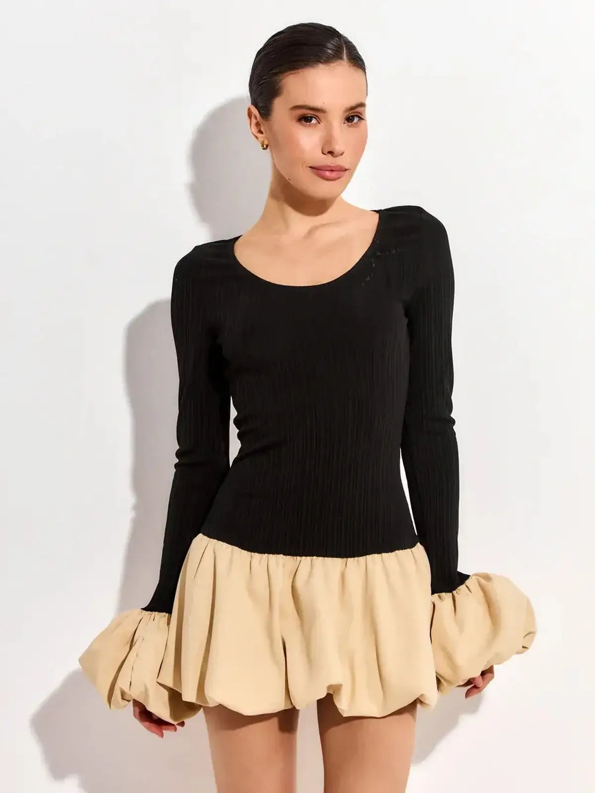 Model wearing a black long sleeve mini dress with a beige voluminous bubble skirt, perfect for summer parties.