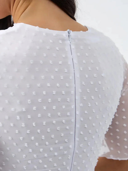 Back view of Starlight Ruffle Mini dress showing delicate polka-dot texture and zipper detail in a white formal dress.