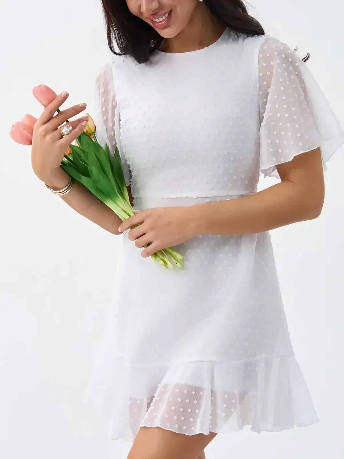 Stylish woman in a Starlight Ruffle Mini white dress with polka dots, holding tulips, perfect for summer and wedding events.