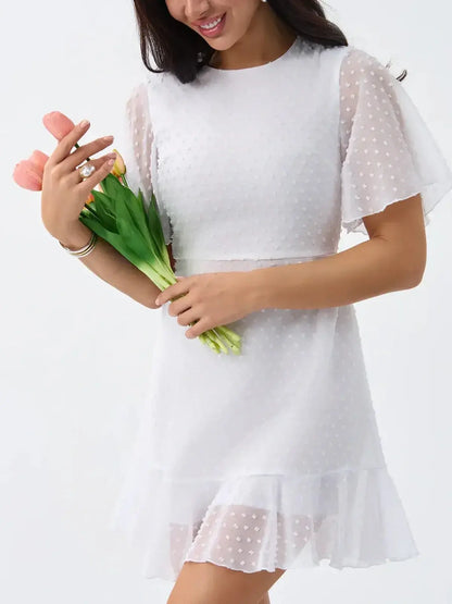 Stylish woman in a Starlight Ruffle Mini white dress with polka dots, holding tulips, perfect for summer and wedding events.