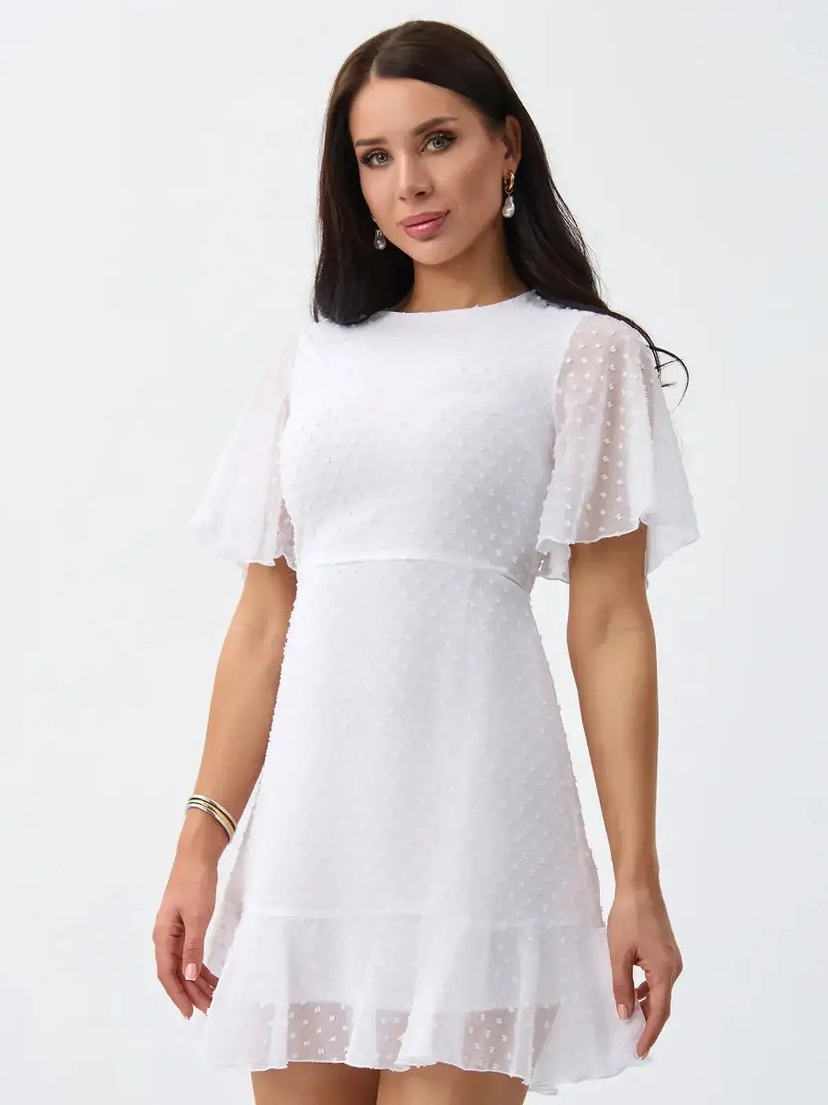 Model wearing the Starlight Ruffle Mini, a white polka-dot dress with flouncy sleeves and hem for summer occasions.