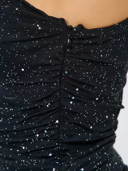 Close-up of the ruched back detailing of the Stellar Glimmer black mini dress with shimmering fabric.