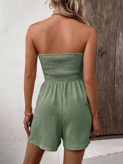 Back view of a woman wearing a green strapless mini dress, showcasing a smocked bodice and relaxed fit.