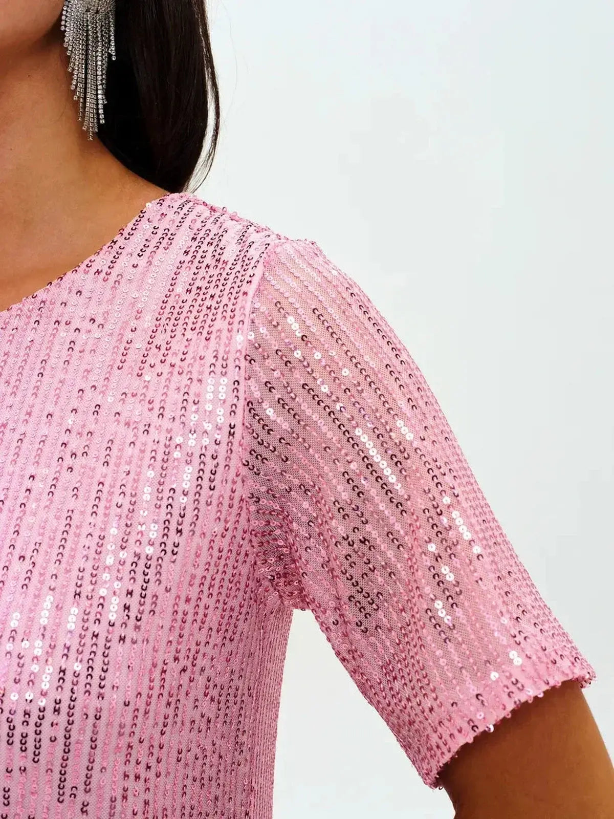 Close-up of a woman wearing a sparkling pink sequin dress with short sleeves, perfect for cocktail and party styling.