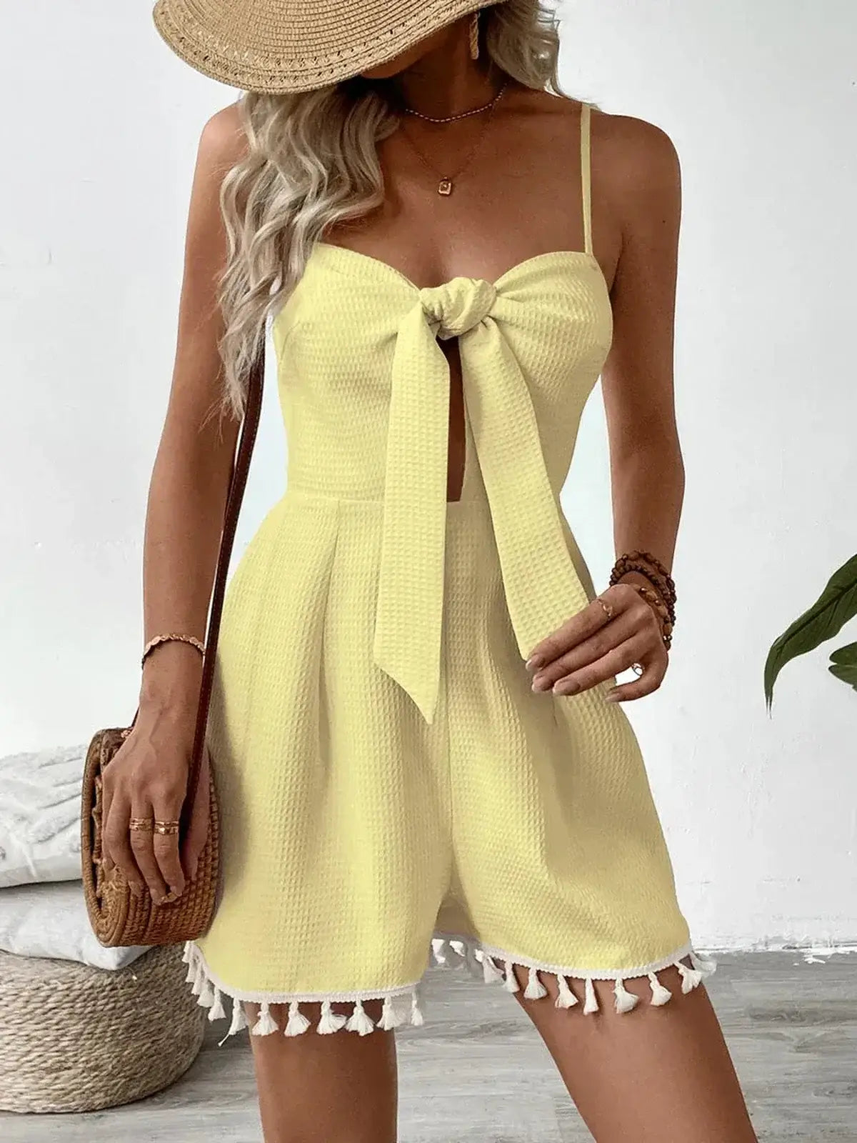 Woman wearing a yellow Sunkissed Mini Dress with a front tie and playful tassels, perfect for summer occasions.