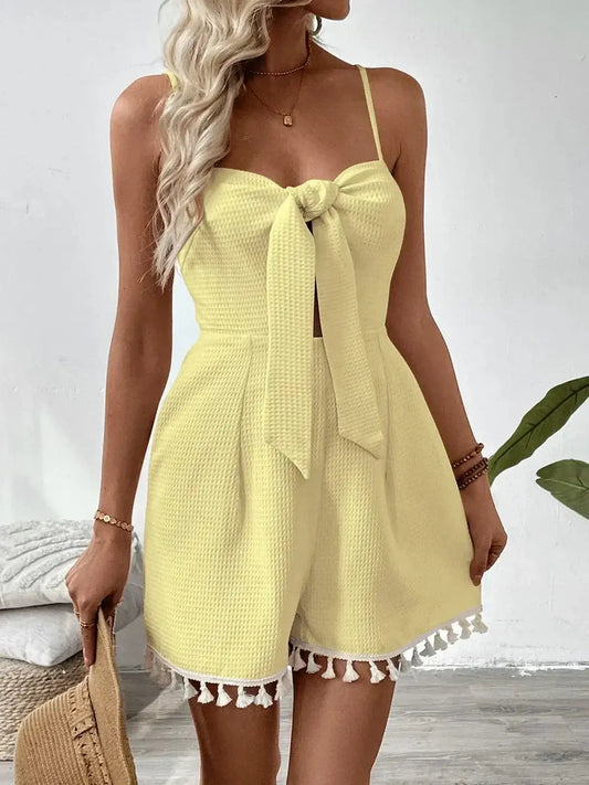 Flirty yellow mini dress with front tie, adjustable straps, and tassel trim, perfect for summer occasions.