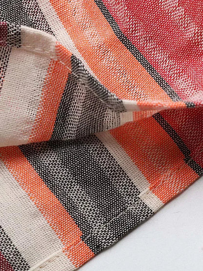 Close-up of vibrant, diagonal stripe fabric featuring mandarin, pink, yellow-orange, and earthy red-brown tones.