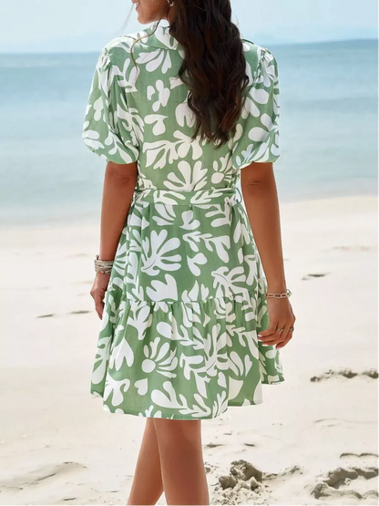 Model wearing the Tropica Breeze Mini Dress with a tropical print, perfect for beach outings and summer occasions.