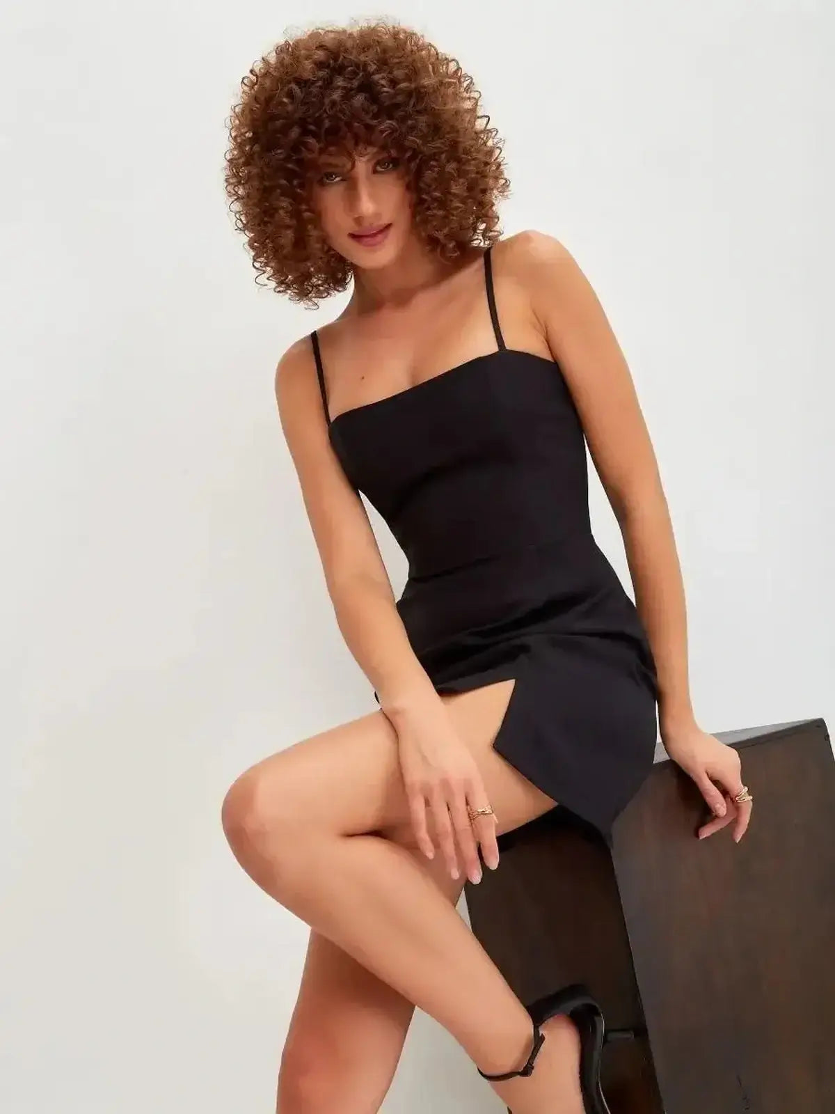 Stylish black mini dress with adjustable straps and front slit, perfect for cocktail events and summer outings.