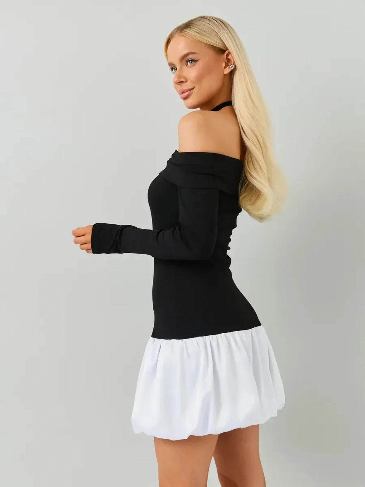Model showcasing a black and white off-the-shoulder mini dress with long sleeves and a bubble skirt.