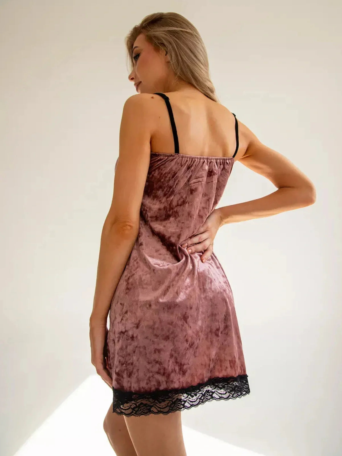Model wearing a velvet blush mini dress with black lace accents, perfect for summer parties or weddings.
