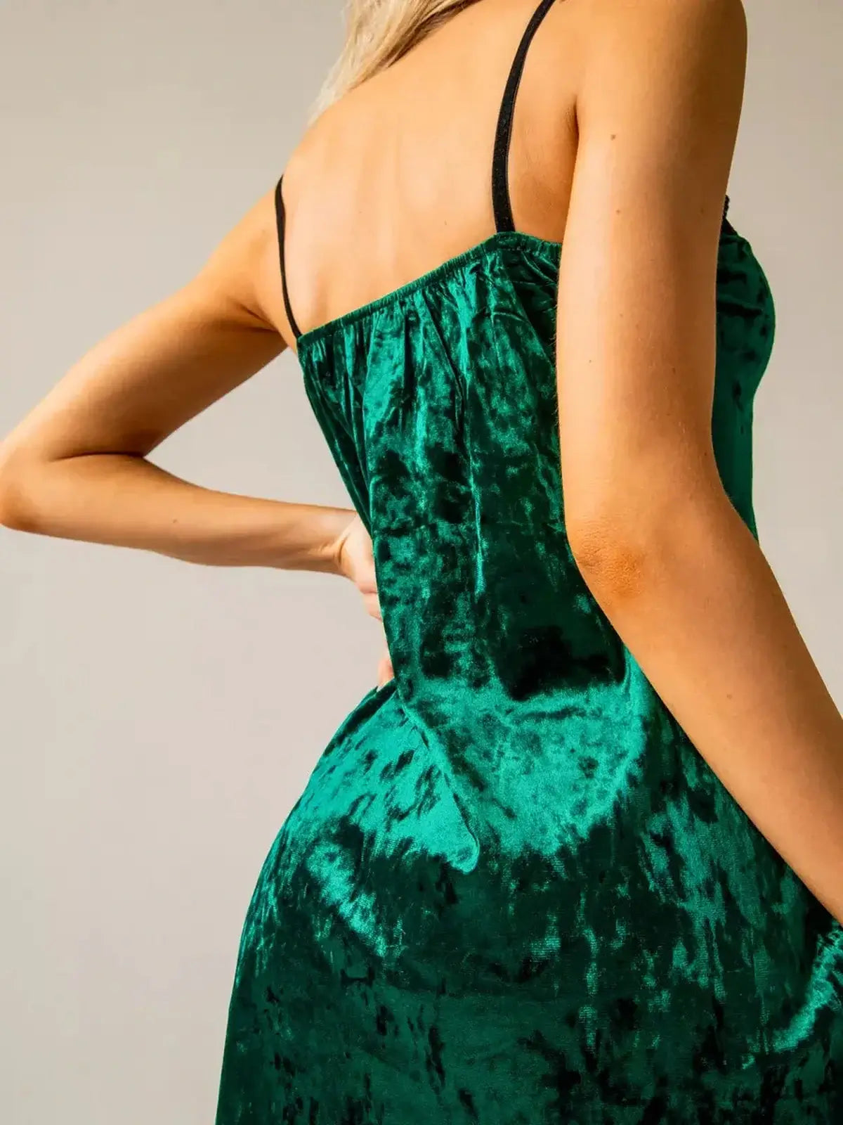 Back view of a lush emerald green velvet mini dress with adjustable straps and a flattering fit.