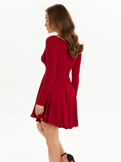 Model wearing a red mini dress with long sleeves and flared skirt, showcasing a playful silhouette.