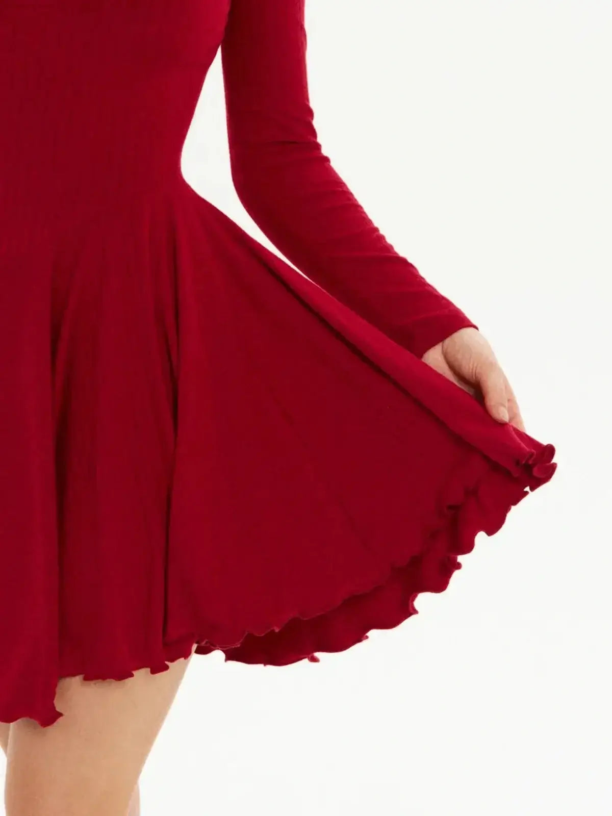 Close-up of a red mini dress featuring a flared skirt with playful ruffle detailing and long fitted sleeves.