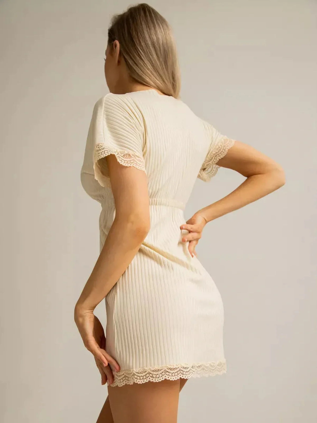 Model wearing a cream ribbed mini dress with lace trim, showcasing a stylish back view.