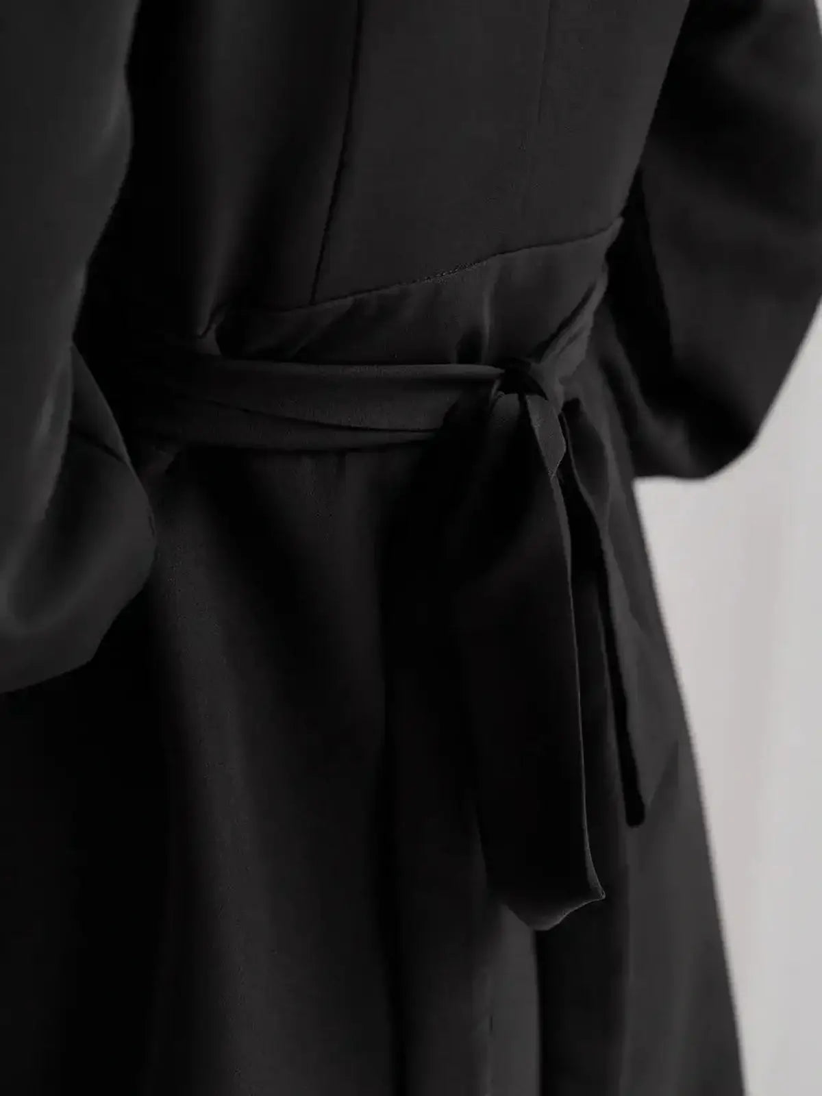 Close-up of the adjustable tie-waist on a stylish black midi dress, showcasing effortless elegance and comfort.
