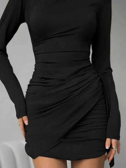 Black mini dress with ruched detailing and long sleeves, perfect for cocktail parties and special occasions.