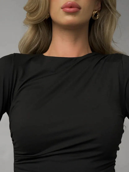 Close-up of a model wearing the Velvet Noir black dress featuring a modern boat neckline and stylish draping.
