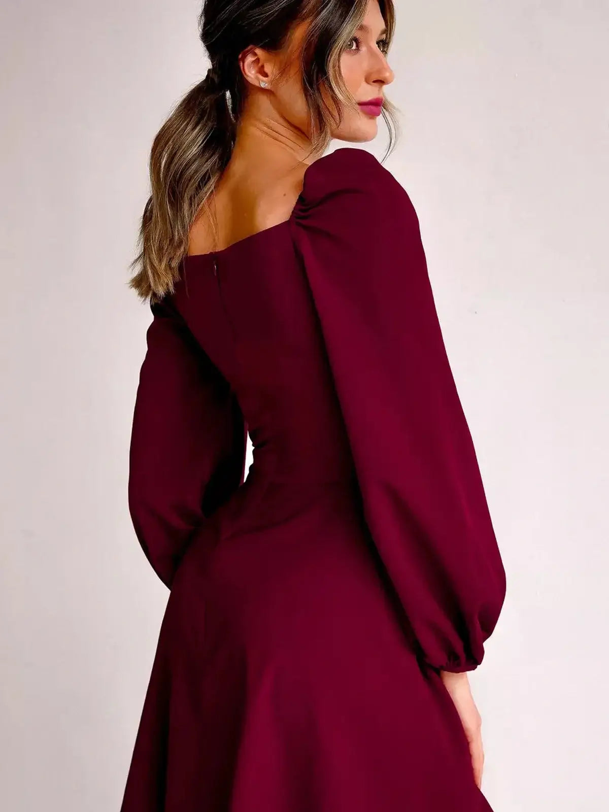 Elegant burgundy mini dress with structured square neckline and voluminous long sleeves, perfect for formal occasions.