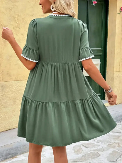 Back view of a green Veranda Bloom Mini Dress with tiered skirt and ruffle sleeves, perfect for summer occasions.