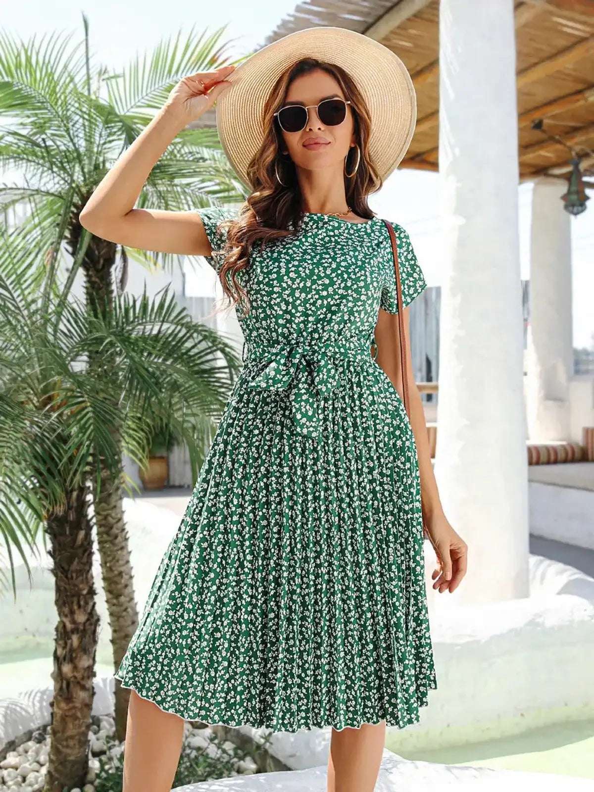 Model in a green floral midi dress with pleated skirt and flutter sleeves, perfect for summer weddings and parties.