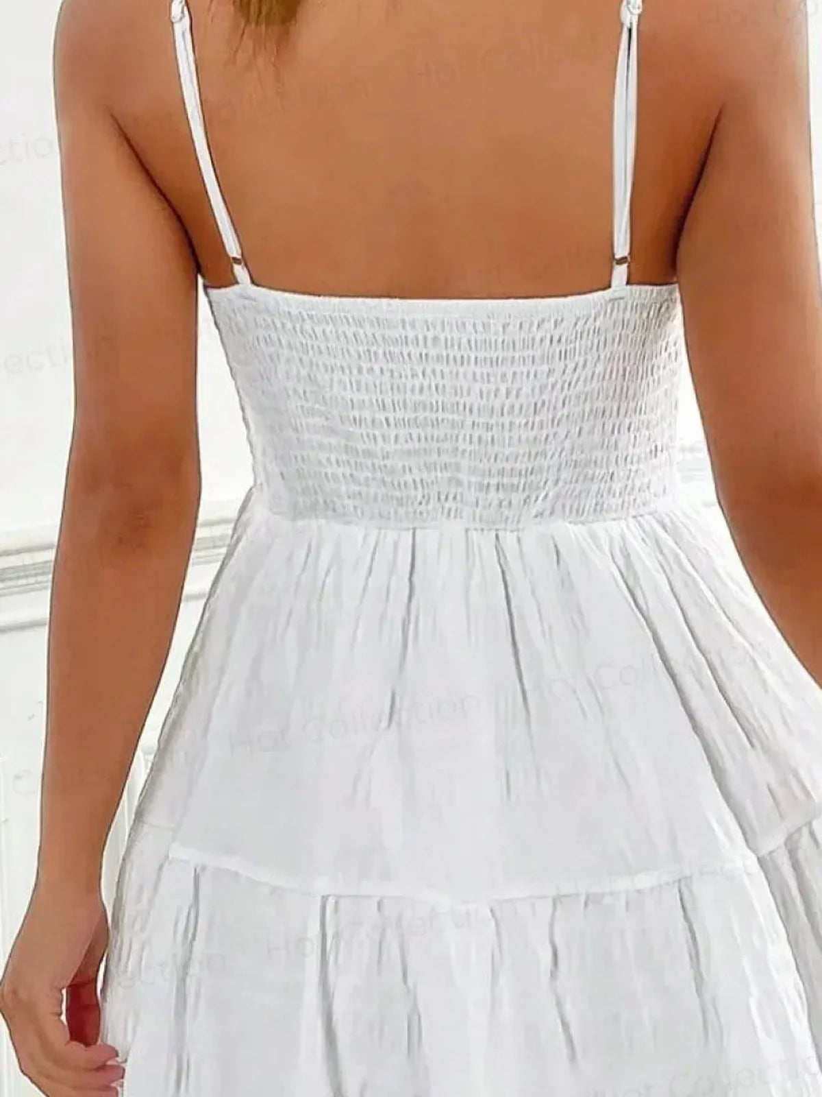 Back view of the Whisper Charm Mini Dress featuring a tiered skirt and delicate spaghetti straps in white.