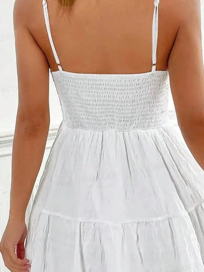 Back view of the Whisper Charm Mini Dress featuring a tiered skirt and delicate spaghetti straps in white.