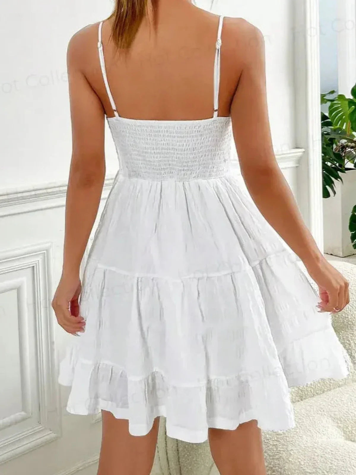 Back view of the Whisper Charm Mini Dress, a white sundress with tiered skirt and spaghetti straps, perfect for summer.