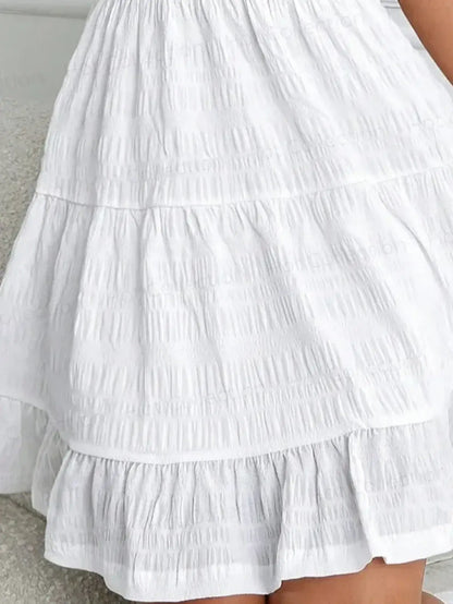 Detail of the Whisper Charm Mini Dress, featuring a breezy tiered white skirt, perfect for summer outings.