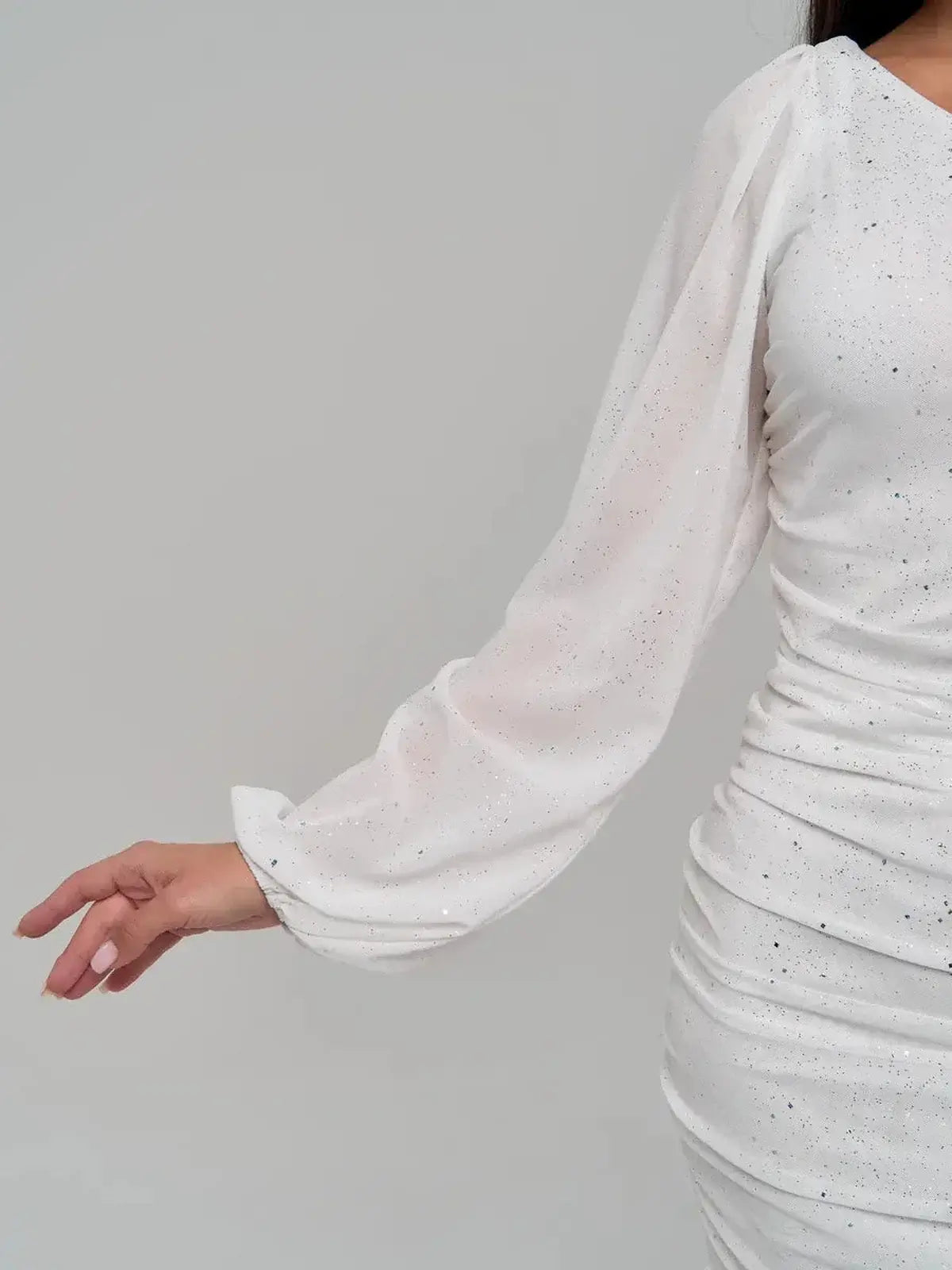 Close-up of white mini dress with sheer puff long sleeve and shimmering sequin details, perfect for elegant occasions.
