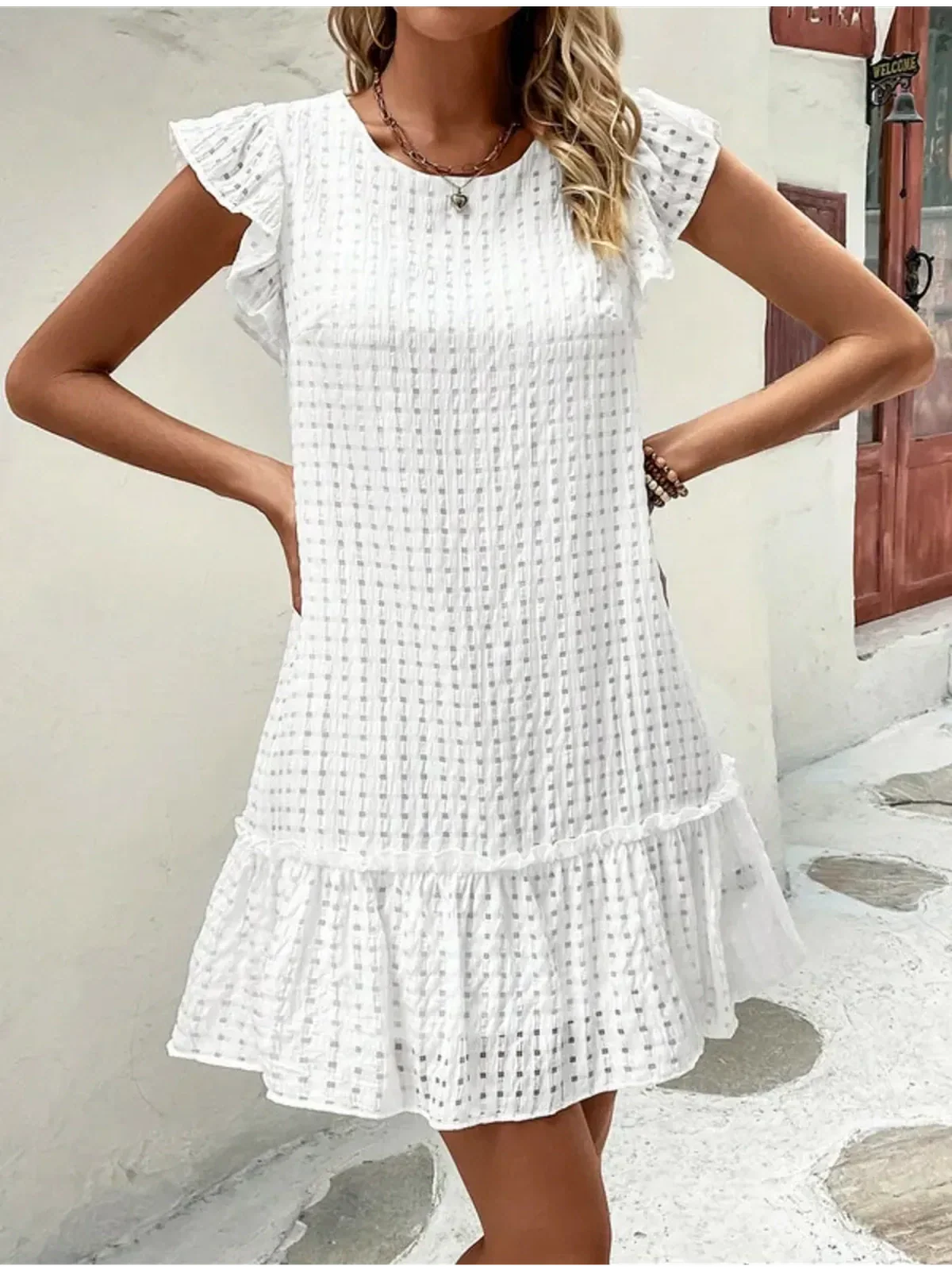 White cotton mini dress featuring ruffled sleeves and a tiered hem, perfect for summer outings or casual events.