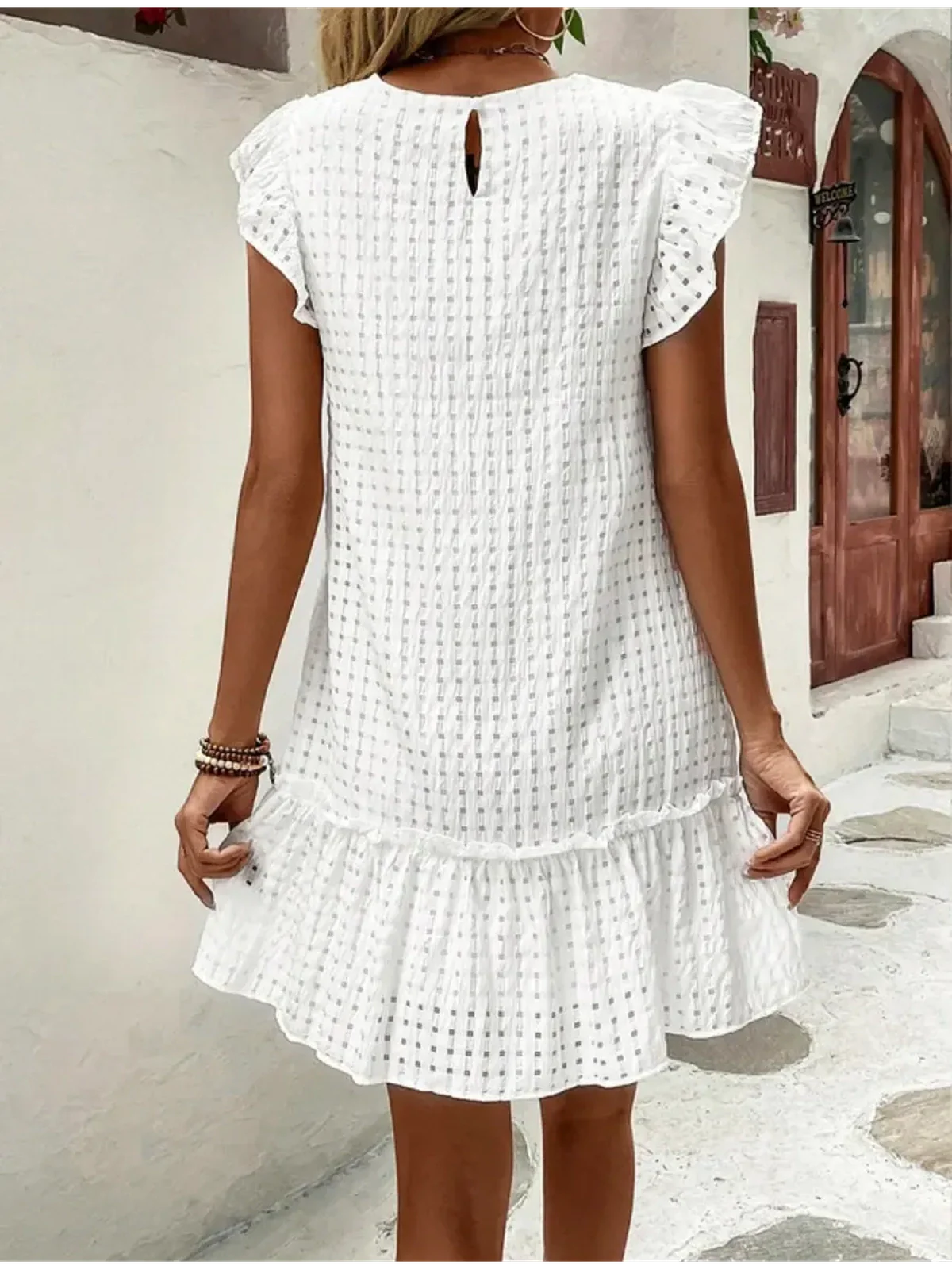 Back view of a white summer dress with ruffled sleeves and hem, perfect for casual occasions or beach outings.