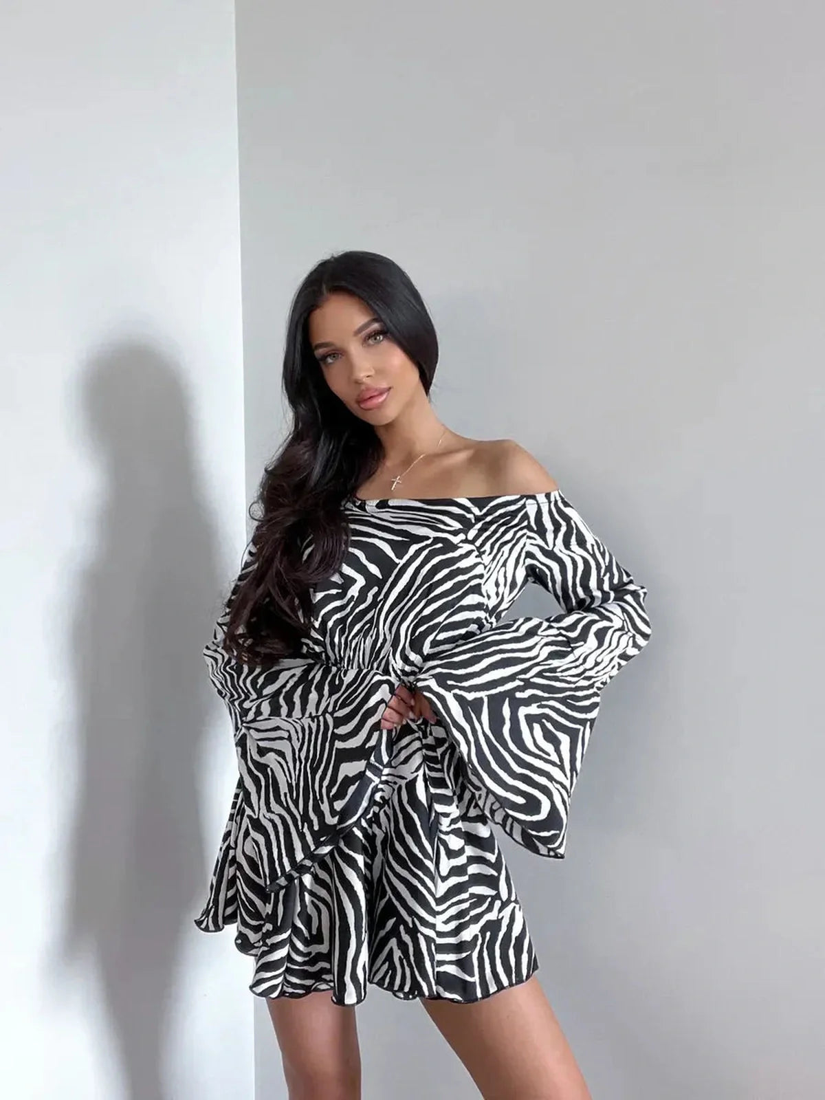 Model wearing Zebra Daze Mini Dress with flared sleeves and off-shoulder neckline, perfect for summer or parties.
