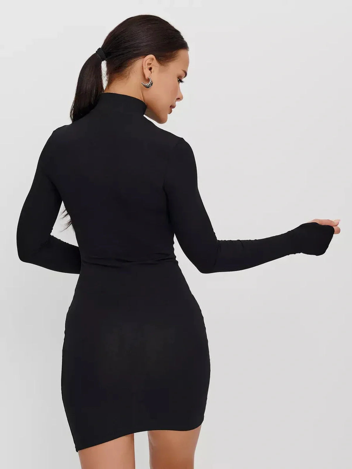 Rear view of a woman wearing a sleek black Zip Form Mini Dress with long sleeves and a high collar.