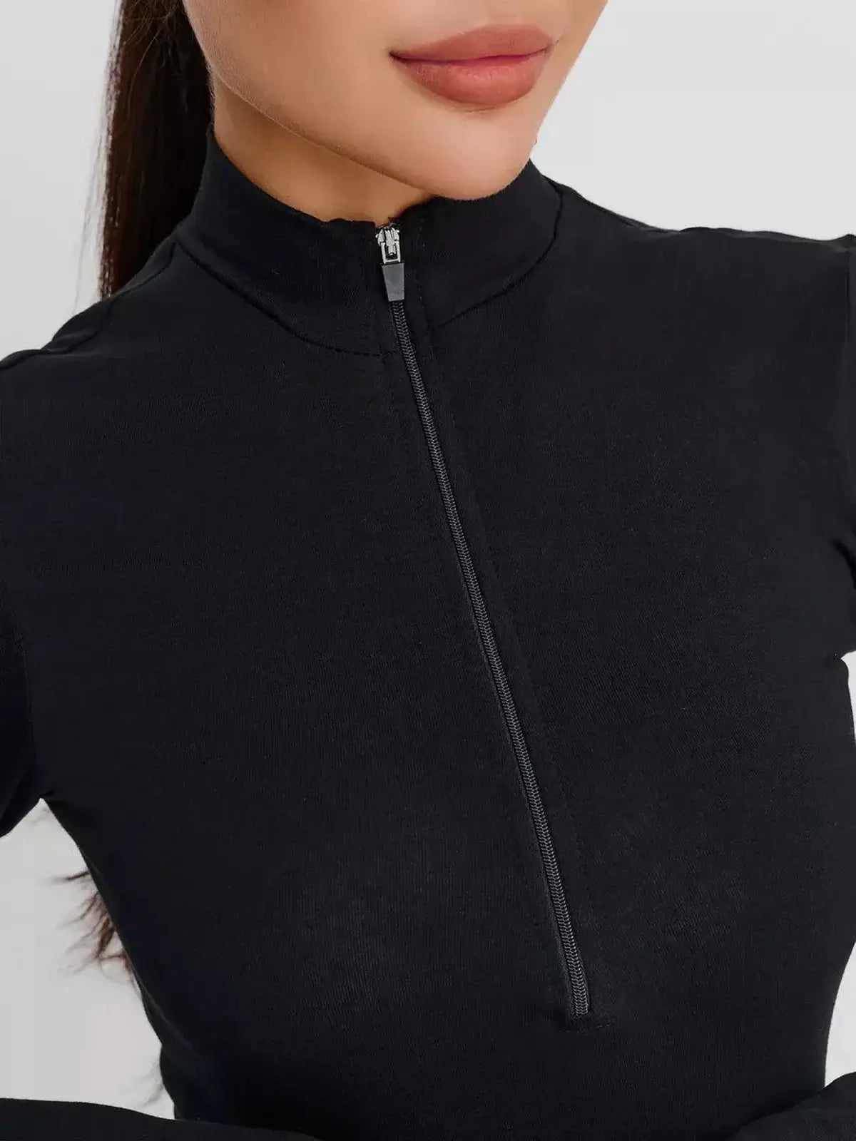 Close-up of a model wearing a sleek black Zip Form Mini Dress with a zip-front closure and high collar.